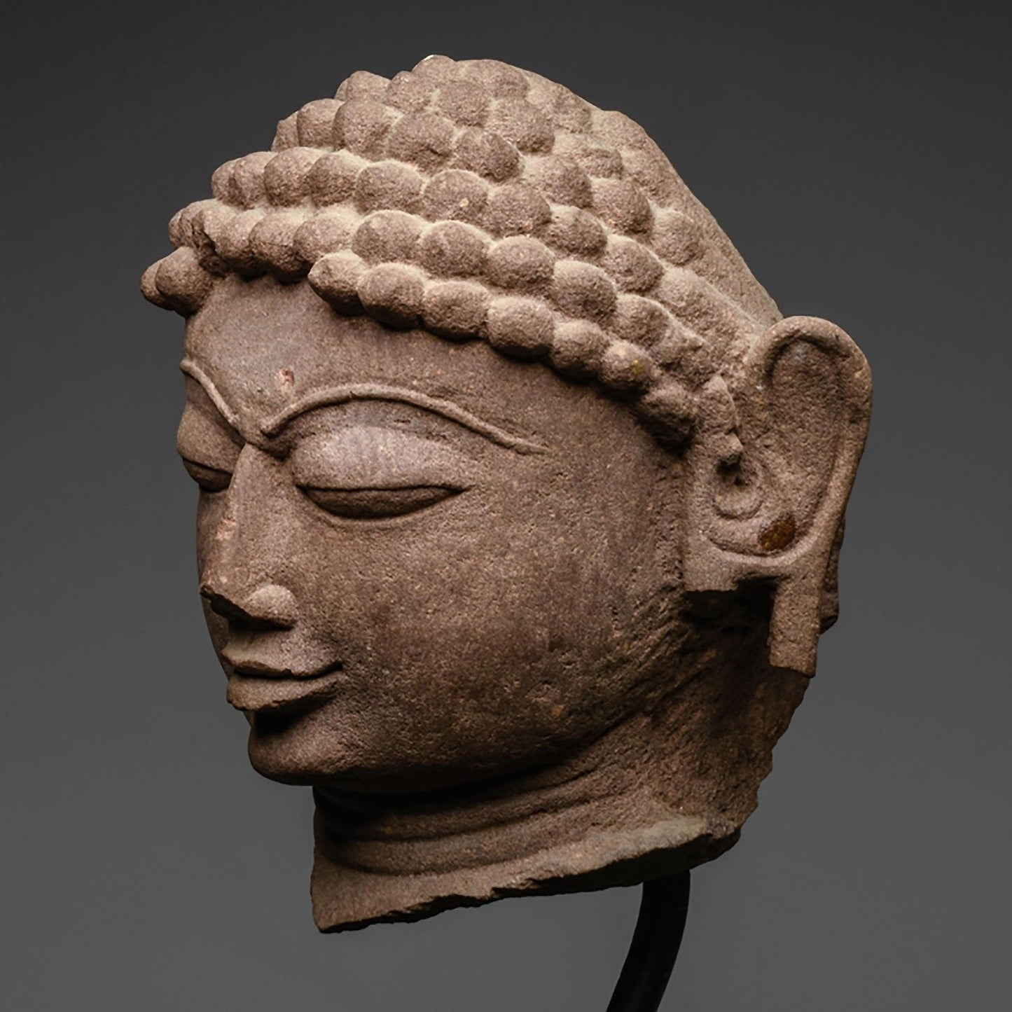 A mottled red sandstone head of a Jina, India, 11th/12th century CE