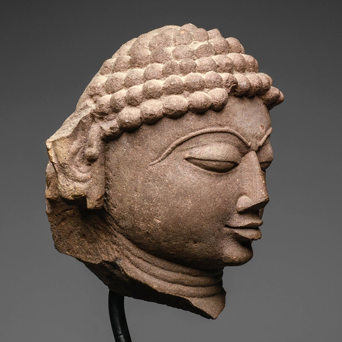 A mottled red sandstone head of a Jina, India, 11th/12th century CE