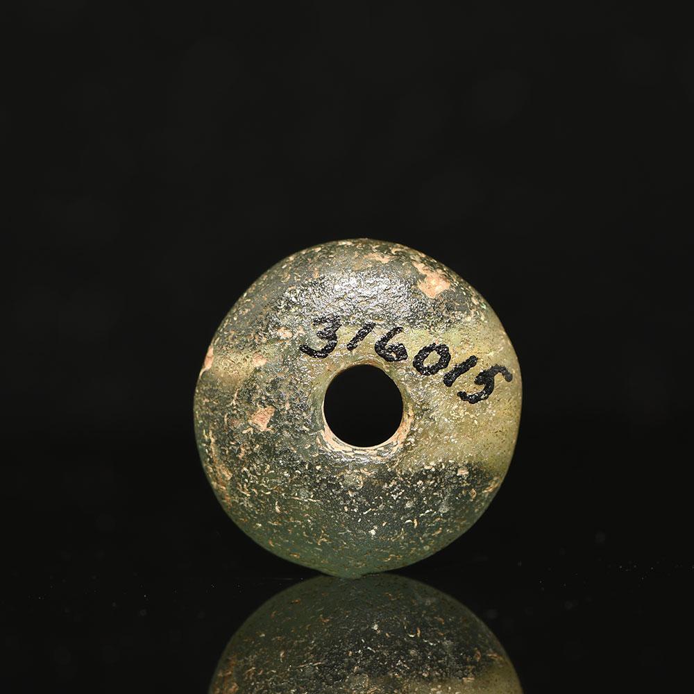 A large Roman Green Glass Bead, ca. 1st - 2nd century CE - ex museum.